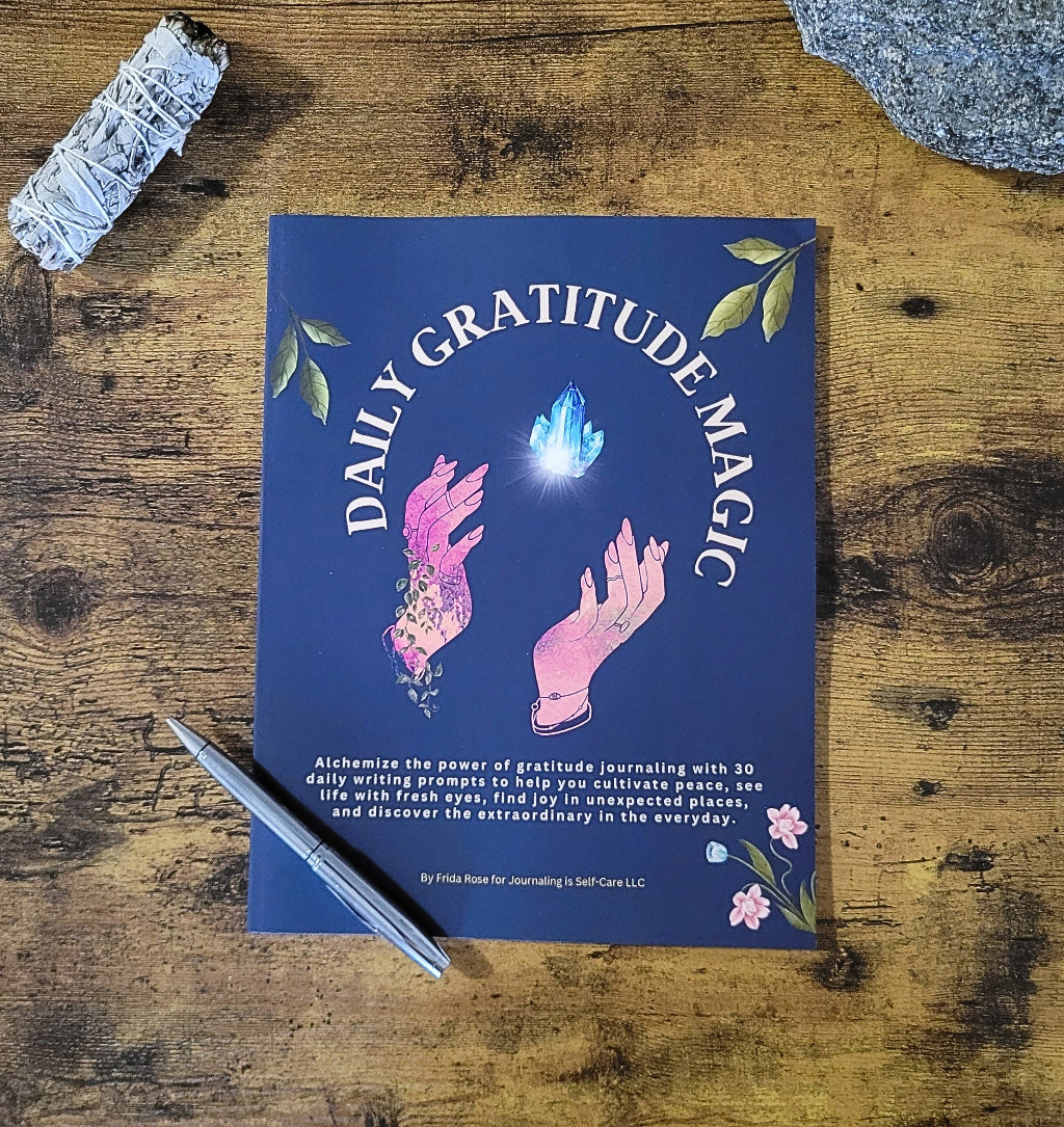 Book titled 'Daily Gratitude Magic' on a wooden surface with a pen and crystals.