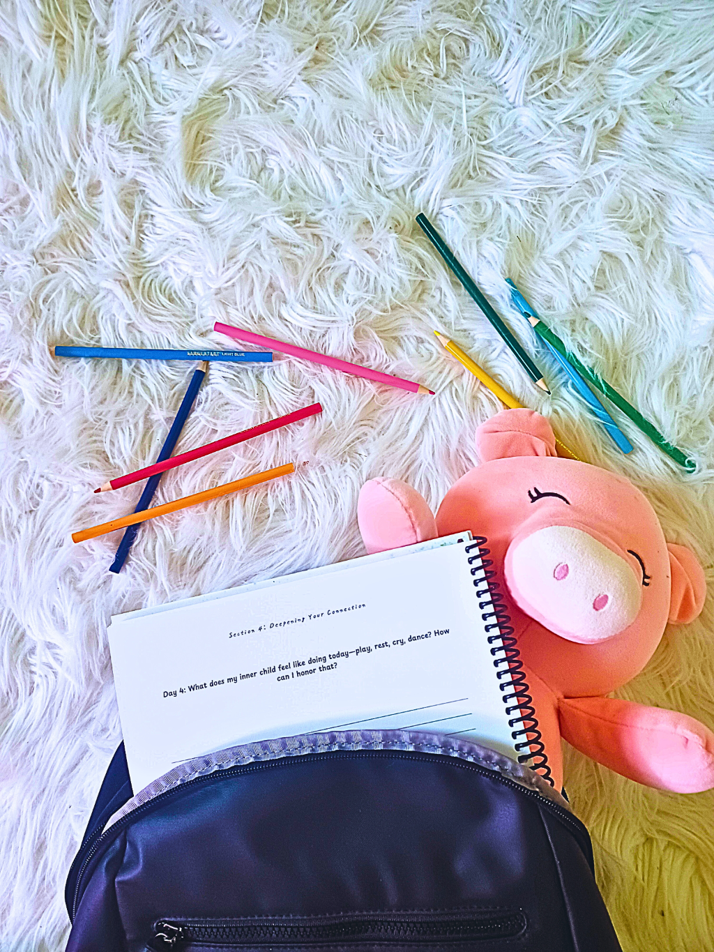 Opened Self-Discovery Journal with colored pencils, and a plush toy on a textured surface