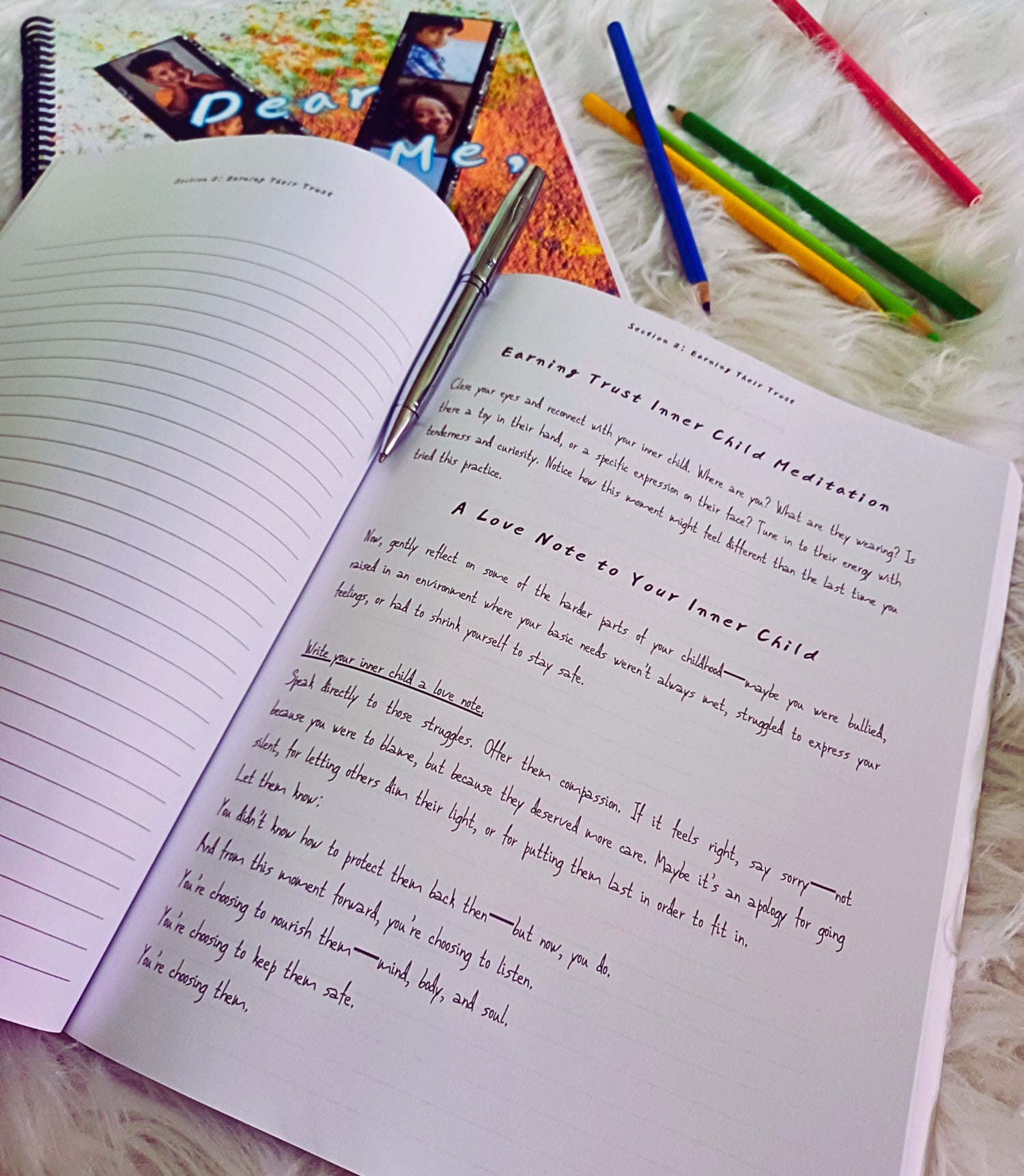 Open book with writing, pen, and colored pencils on a textured surface