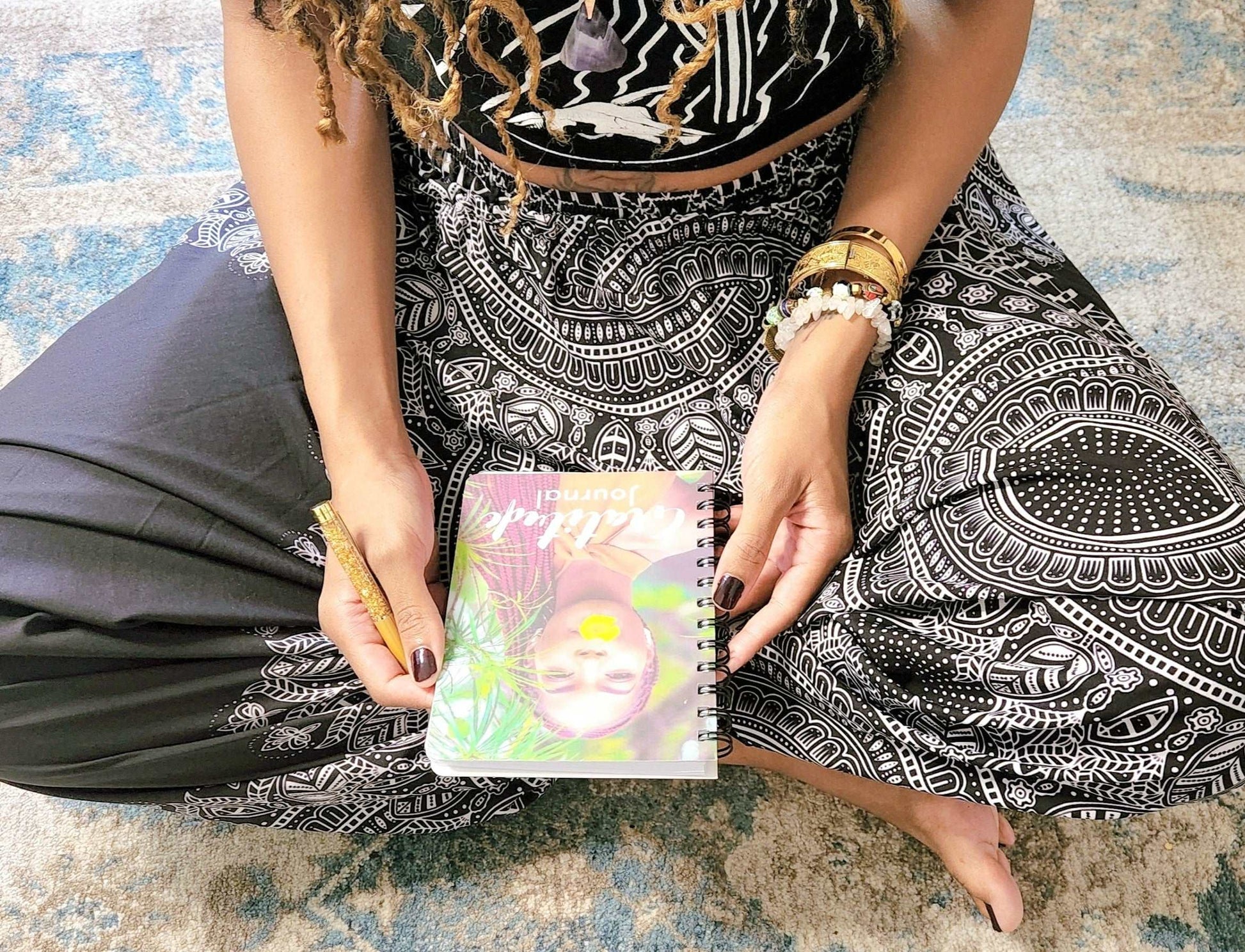 A grateful woman sitting on the floor holding a Gratitude Journal : A Journal For Women.