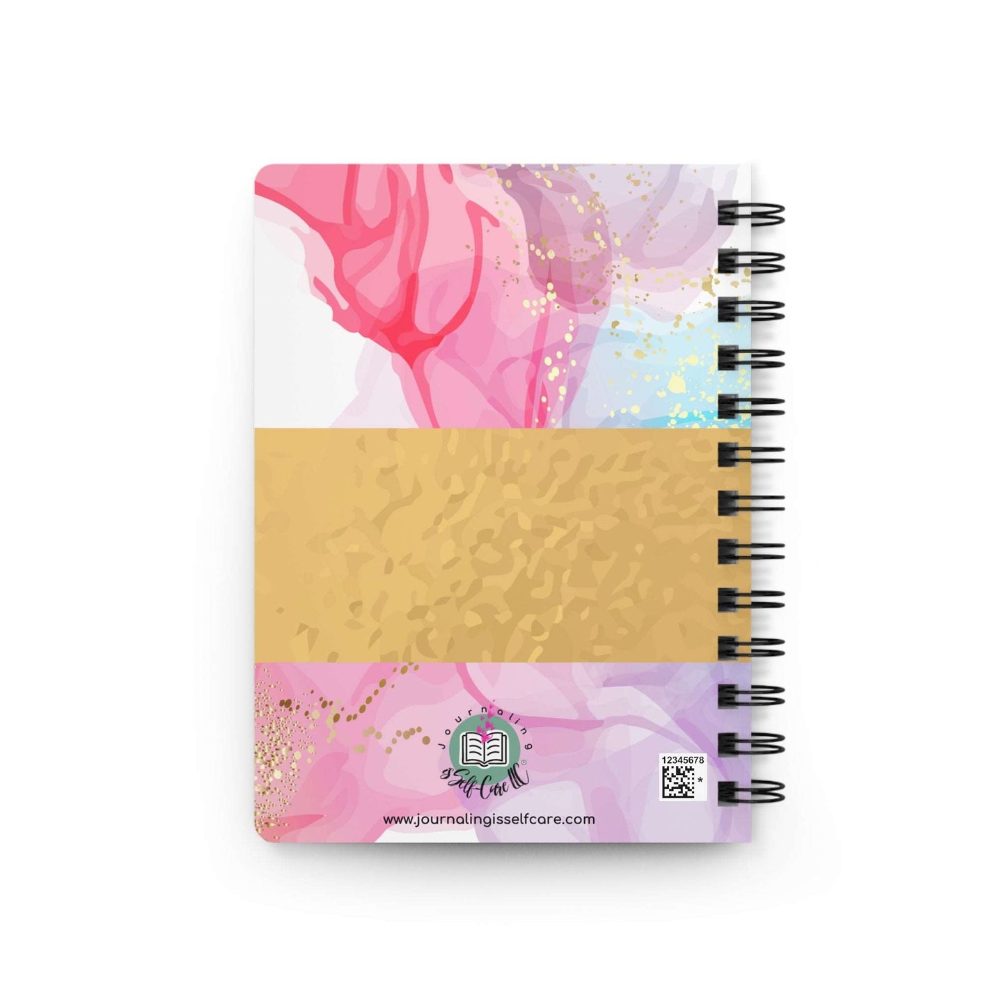 A spiral notebook with a pink and gold cover, perfect for capturing moments of gratitude in a Grateful Journal.