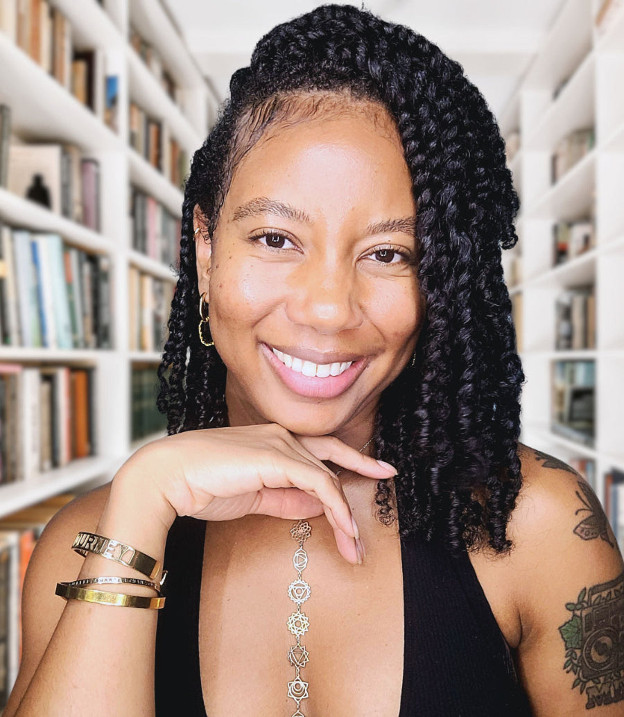 Frida Rose with twisted hair smiling in front of a bookshelf