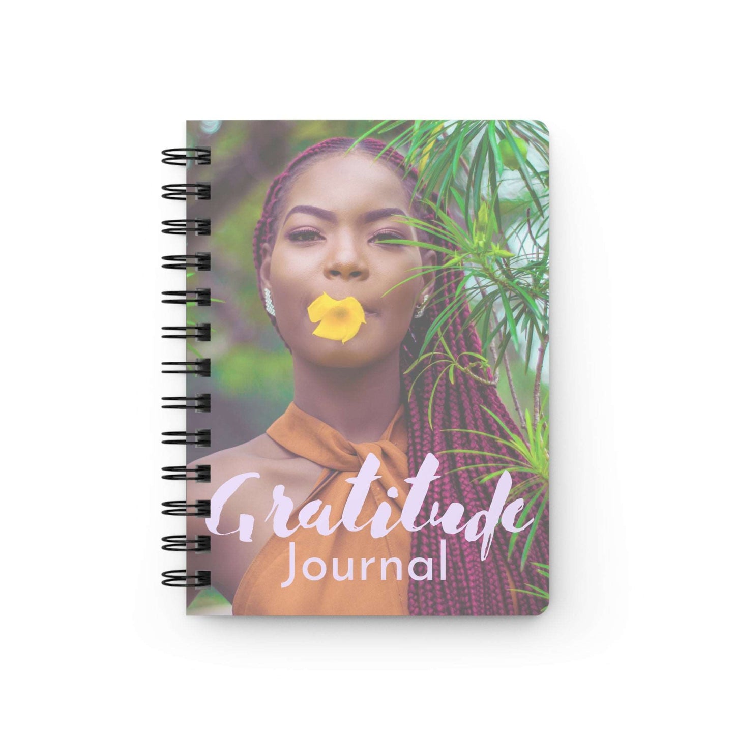 A spiral notebook with the words "Gratitude Journal : A Journal For Women" on it.