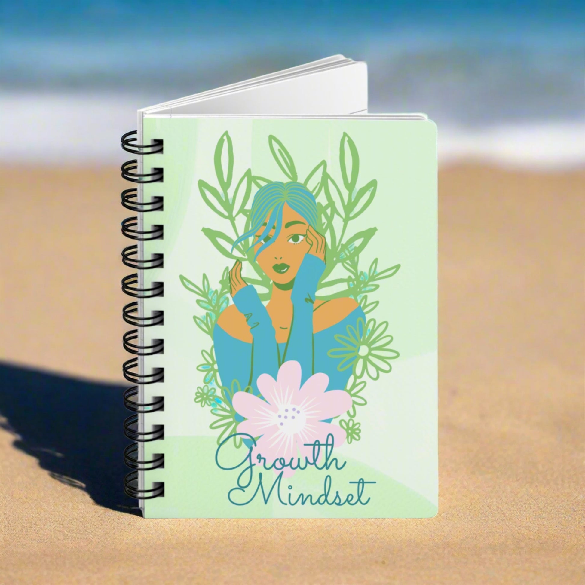 A green spiral notebook with the words "Growth Mindset" Inspirational Journal for Success and Self Improvement on it, serving as a reflective journal for emotional intelligence and growth mindset.