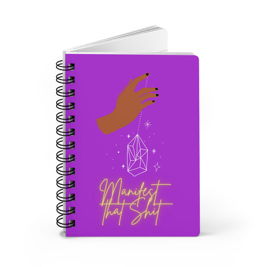 A purple spiral "Manifest That Shit" Manifesting Journal for Scripting with a hand holding a crystal.