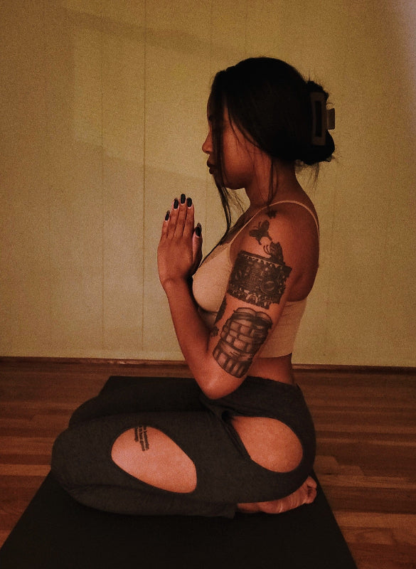 Person with tattoos practicing yoga in a studio setting