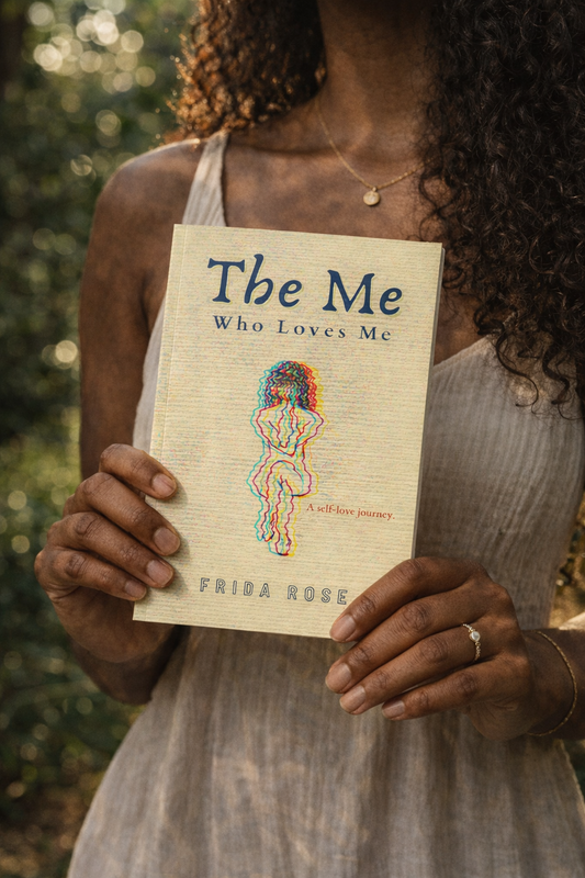 Person holding a book titled 'The Me Who Loves Me' by Frida Rose against a blurred natural background.

