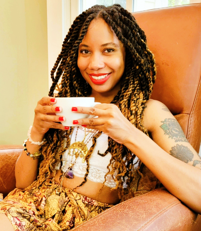 Woman sitting on a brown leather couch holding a white mug with a red interior.