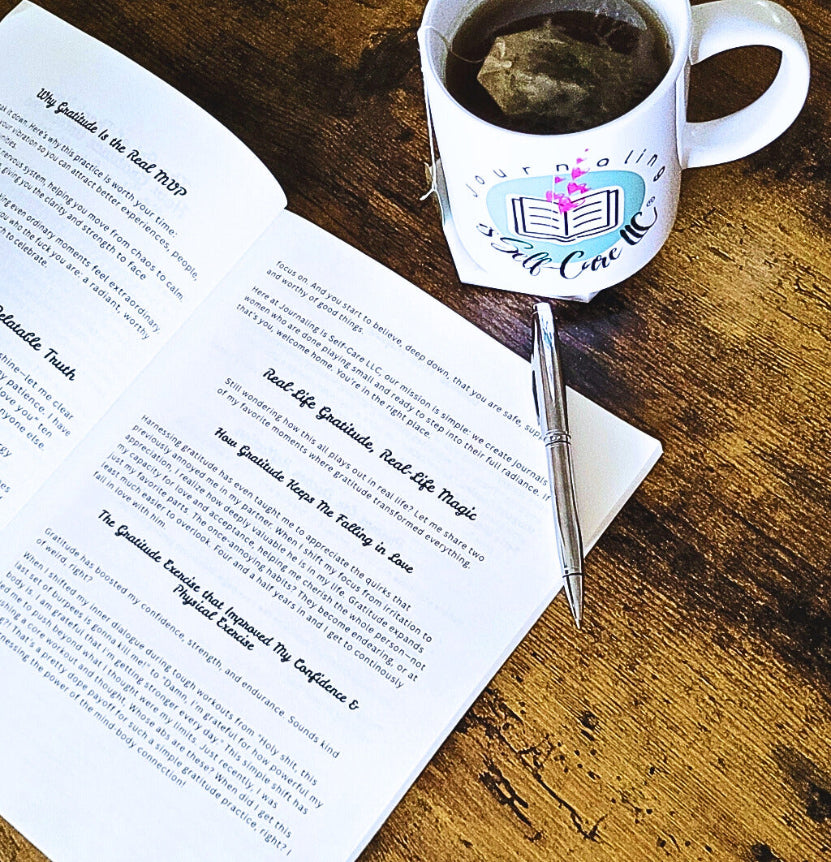 Open book with a pen on a wooden surface next to a mug with a tea bag.