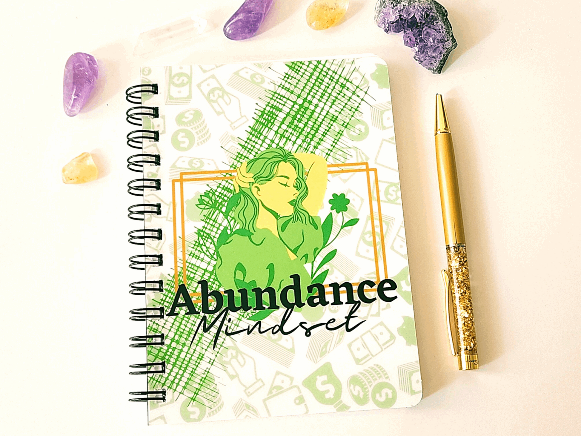 A spiral notebook adorned with the word "abundance" and featuring journal prompts to cultivate an Abundance Mindset Journal with Journal Prompts.