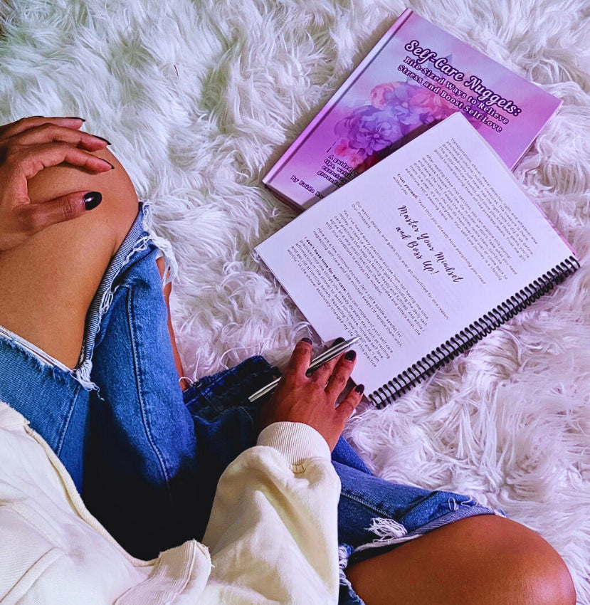 Person lying on a fluffy white rug with an open book and pen