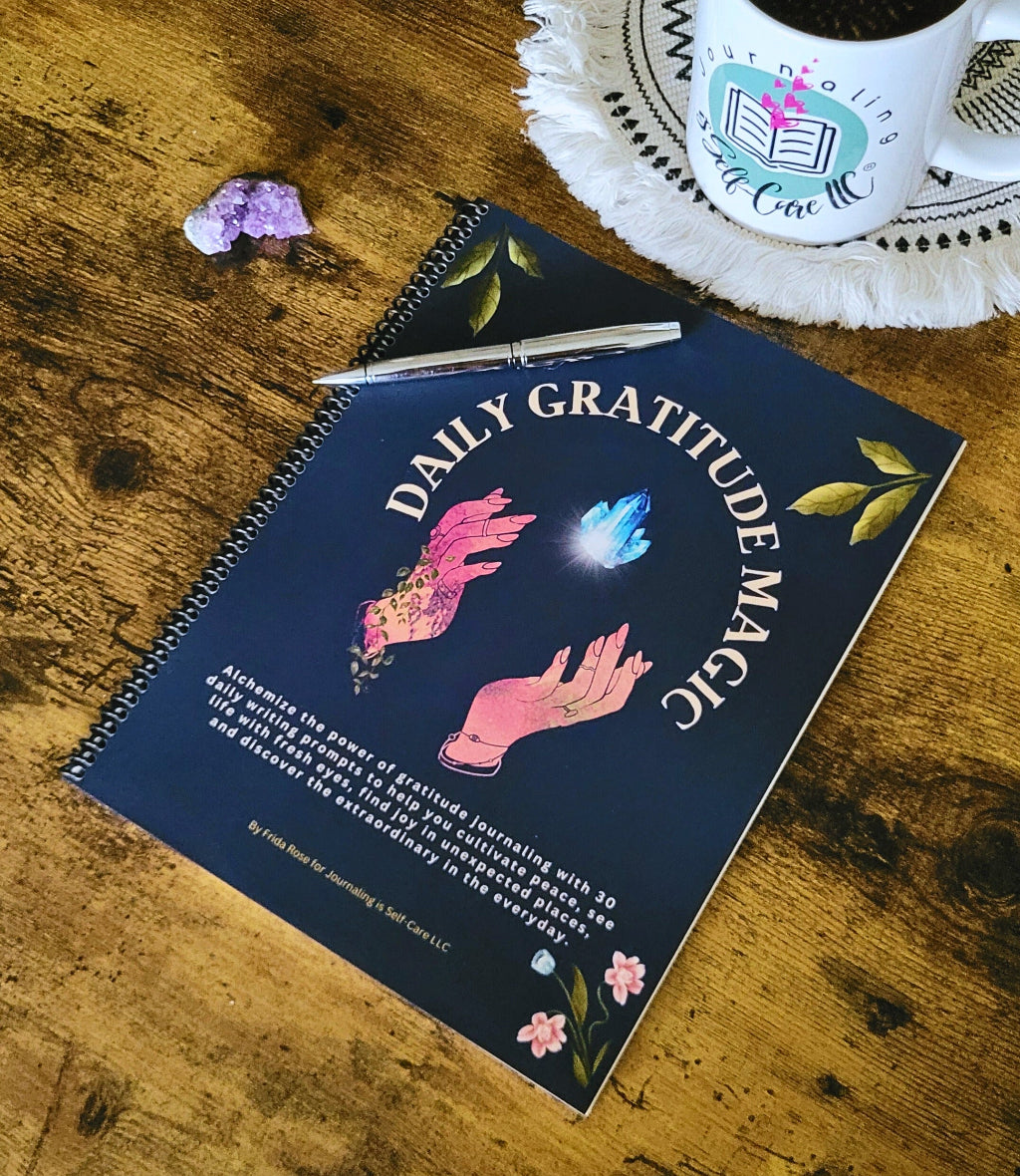 Daily Gratitude Magic notebook on a wooden surface with a mug and flowers.