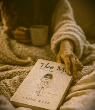 Person holding a book titled 'The Me Who Loves Me' by Frida Rose, with a warm-toned filter.