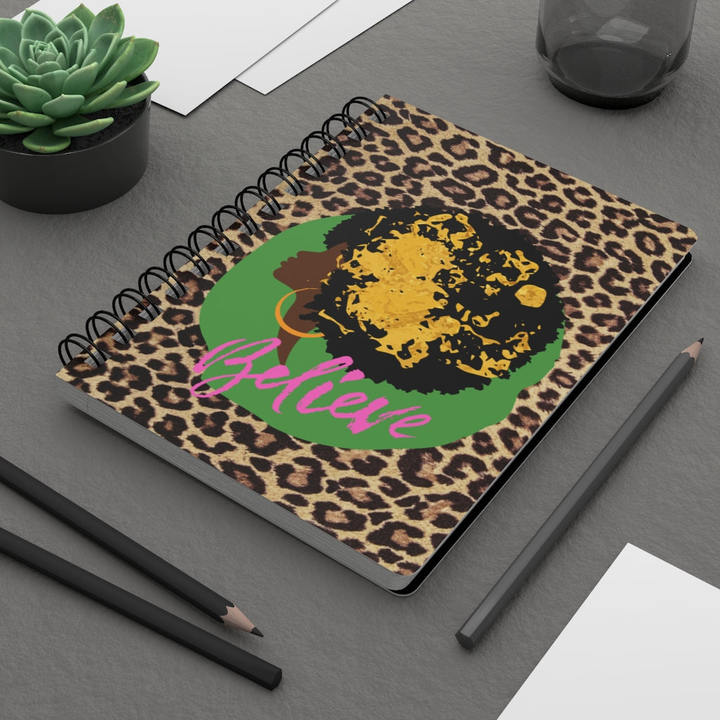 A spiral notebook with a leopard print cover and a pen, perfect for capturing moments of Black Girl Magic or jotting down journal prompts in the "Believe in Your Dreams" Inspirational Black Girl Magic Journal.