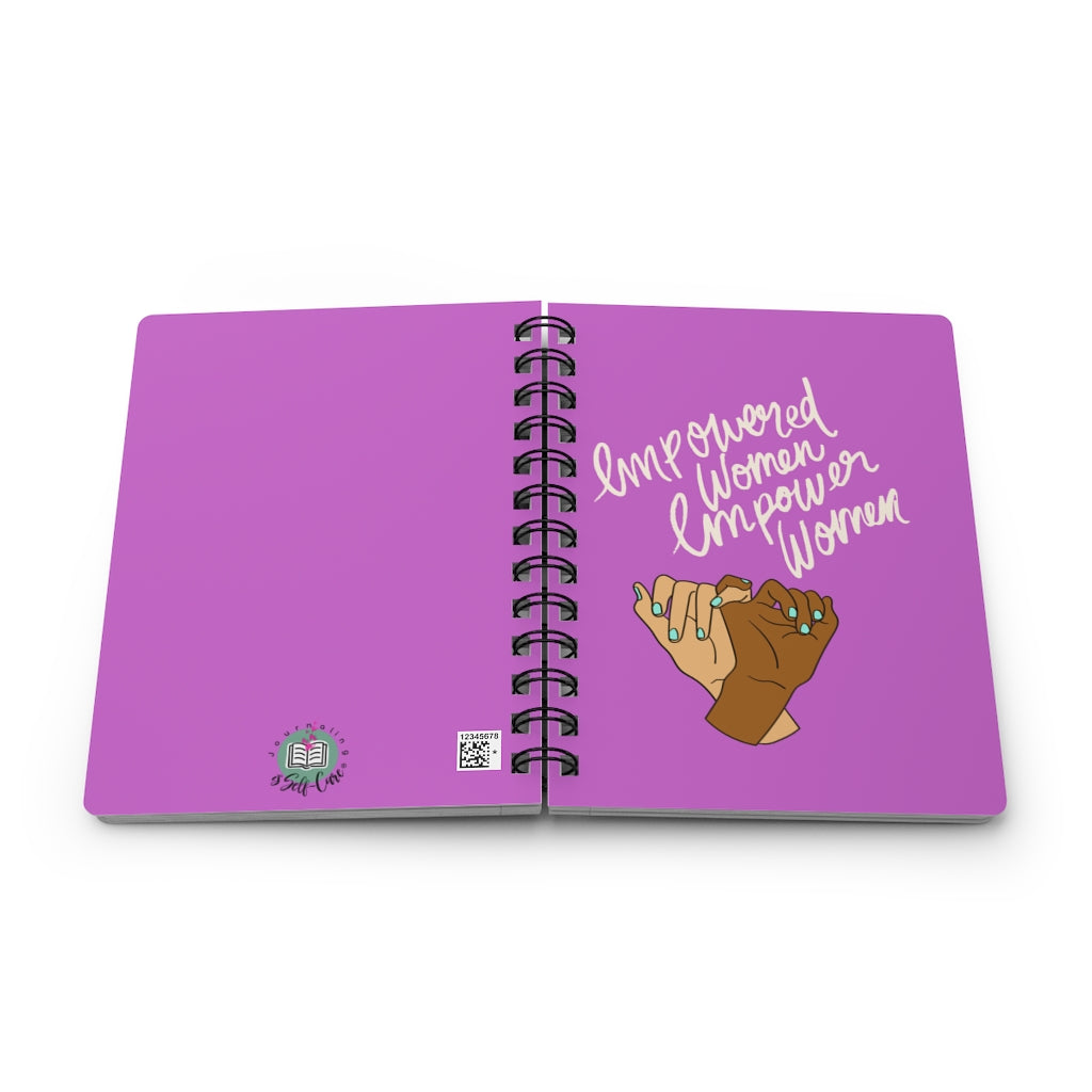 A purple spiral notebook featuring the "Empowered Women Empower Women" Women's Empowerment Journal.